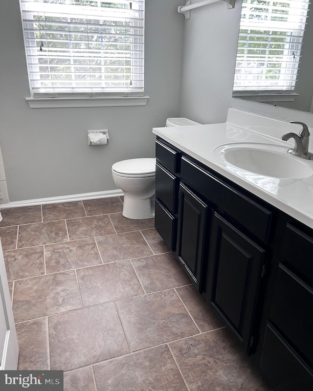 bathroom with toilet, vanity, and baseboards