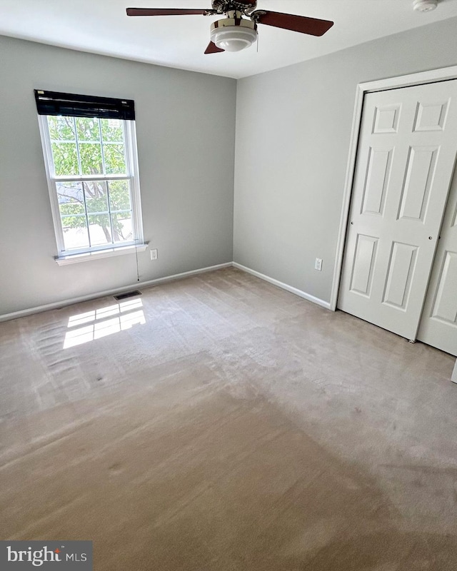 unfurnished bedroom with carpet flooring, baseboards, a closet, and ceiling fan