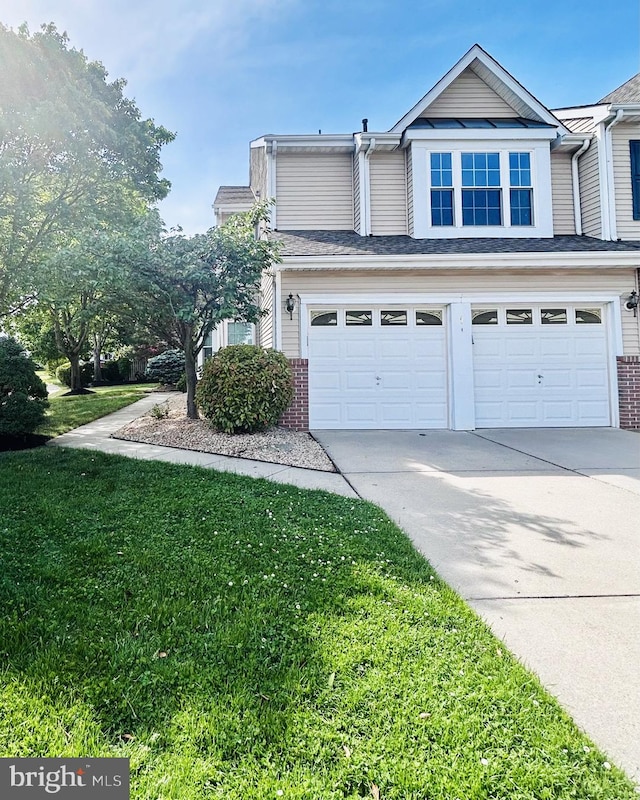 view of side of home featuring a garage, driveway, brick siding, and a lawn
