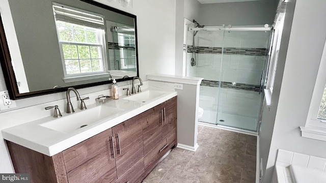 full bathroom featuring a stall shower, toilet, double vanity, and tile patterned floors