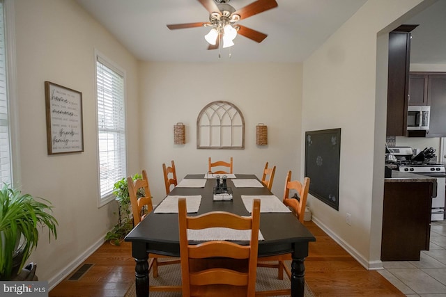 dining space with ceiling fan, light wood-style flooring, and baseboards