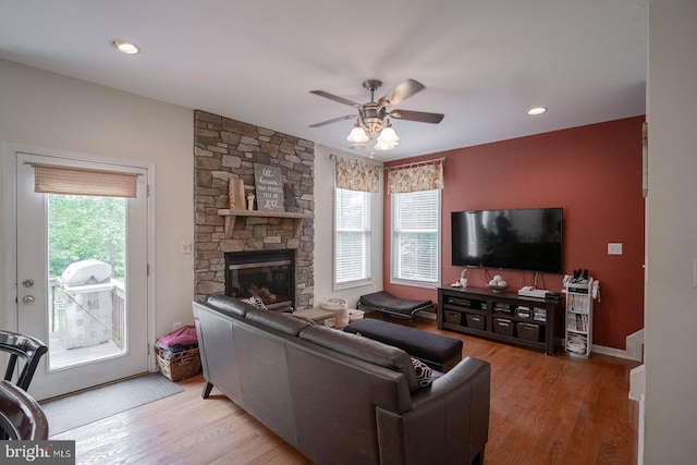 living area with ceiling fan, wood finished floors, a stone fireplace, and recessed lighting