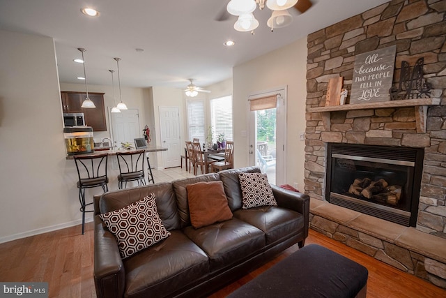 living area with a ceiling fan, wood finished floors, baseboards, a fireplace, and recessed lighting