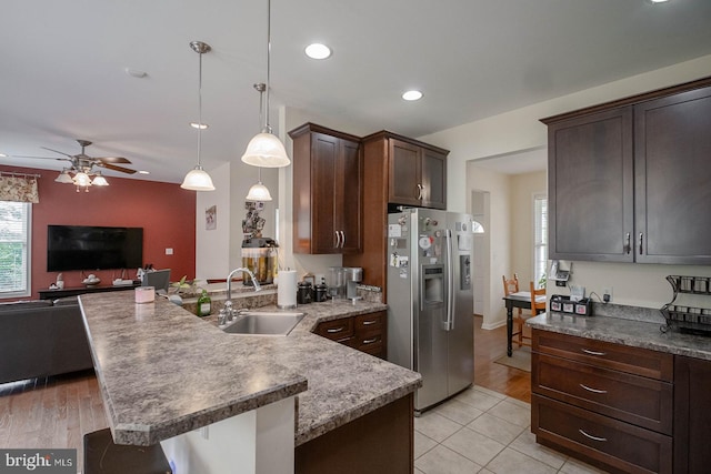 kitchen featuring stainless steel fridge, a sink, open floor plan, ceiling fan, and a peninsula