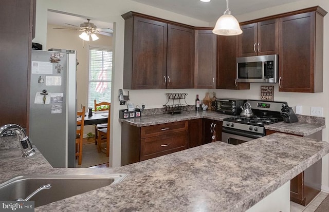kitchen featuring stainless steel appliances, a sink, dark brown cabinets, a ceiling fan, and pendant lighting