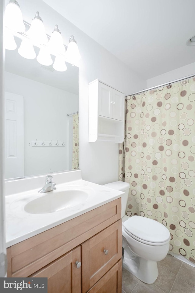 bathroom with toilet, vanity, and tile patterned floors