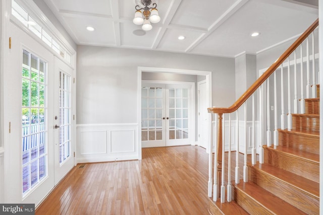entrance foyer with french doors, a chandelier, stairway, hardwood / wood-style flooring, and coffered ceiling