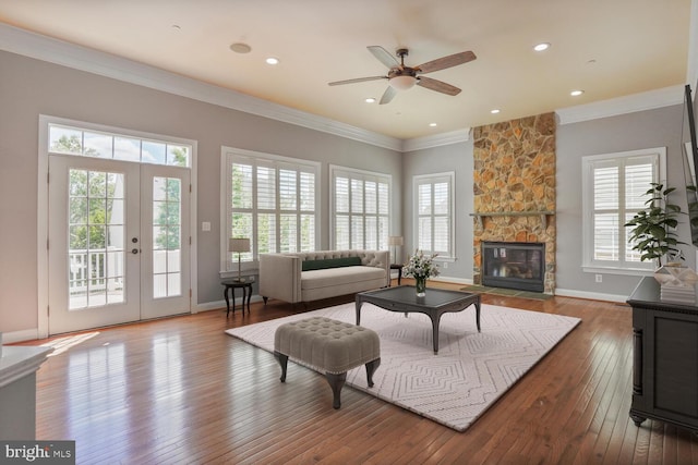 living area with crown molding, hardwood / wood-style floors, a fireplace, ceiling fan, and french doors