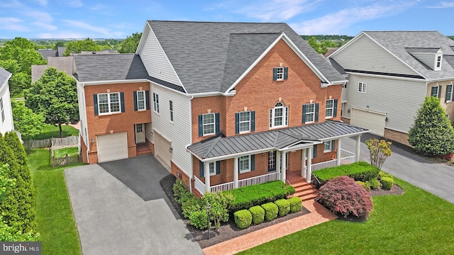 view of front of property featuring brick siding, a porch, driveway, a garage, and a standing seam roof