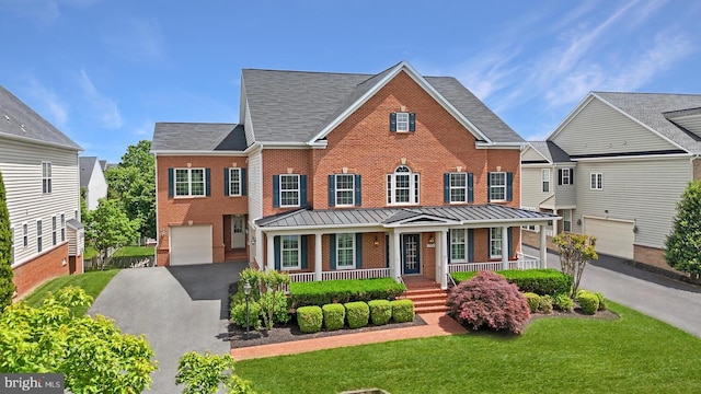 view of front facade featuring a porch, brick siding, driveway, a standing seam roof, and a garage