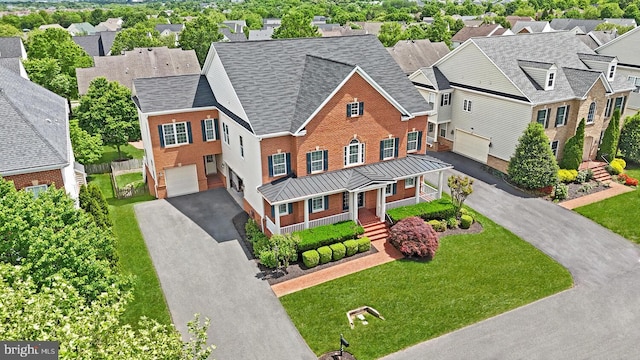 view of front of property featuring driveway, a garage, a residential view, brick siding, and roof with shingles