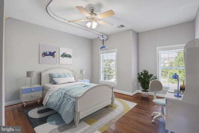 bedroom with baseboards, wood finished floors, an office area, and a ceiling fan
