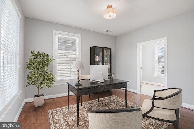 office space featuring healthy amount of natural light, wood finished floors, and baseboards