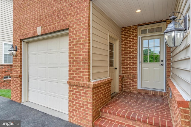doorway to property with brick siding and a garage