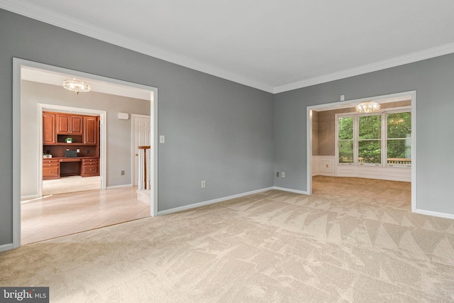 unfurnished room featuring a chandelier, ornamental molding, light colored carpet, and baseboards