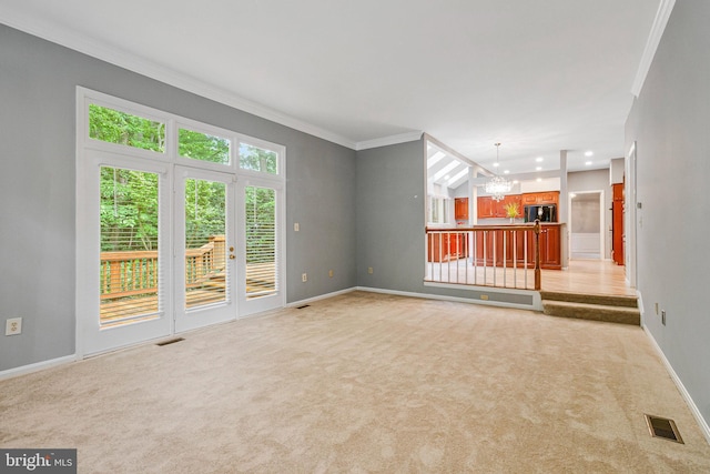 unfurnished living room featuring a chandelier, light colored carpet, crown molding, and baseboards