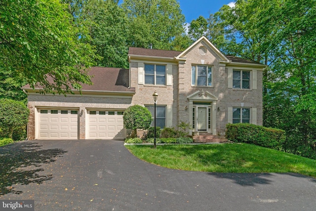 view of front facade with asphalt driveway, an attached garage, brick siding, and a front yard