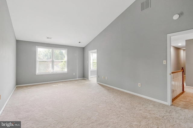 carpeted empty room featuring baseboards and high vaulted ceiling