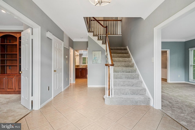 stairway with tile patterned floors, crown molding, carpet, and baseboards