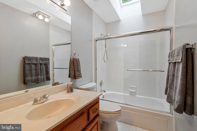 bathroom with toilet, vanity, tile patterned floors, a skylight, and shower / bath combination with glass door