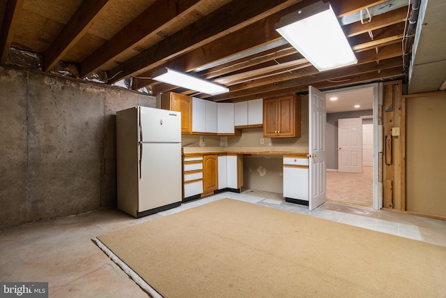 unfinished basement with freestanding refrigerator