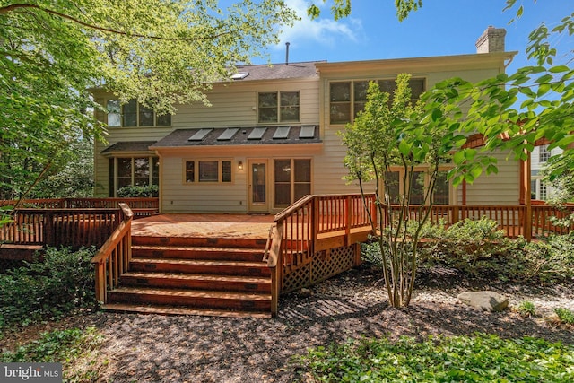 rear view of property featuring a wooden deck and a chimney