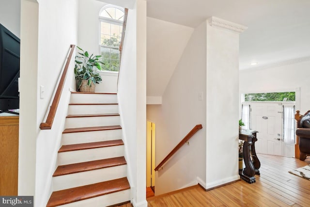 stairway featuring healthy amount of natural light, wood finished floors, and baseboards