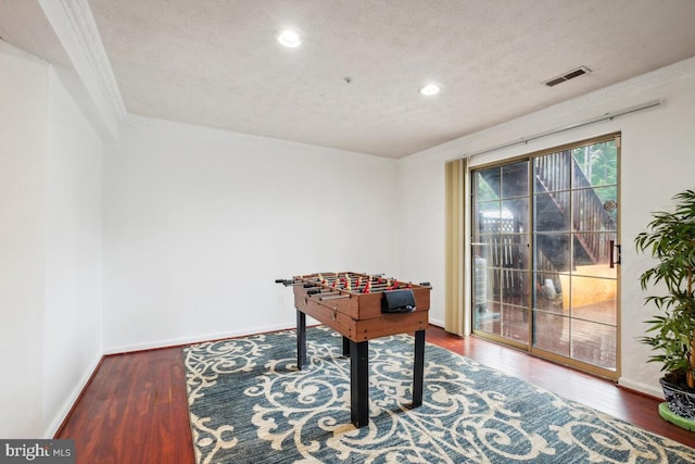 playroom with wood finished floors, a textured ceiling, baseboards, recessed lighting, and crown molding