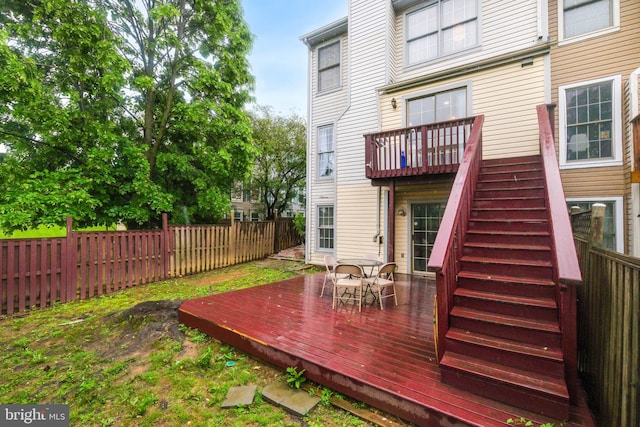 back of property with a fenced backyard, a deck, and stairway