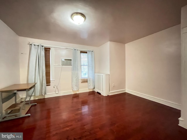empty room with wood finished floors, baseboards, and a wall mounted AC