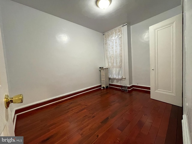 laundry area with radiator heating unit, wood finished floors, and baseboards