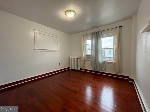 unfurnished room with radiator heating unit, wood finished floors, and baseboards