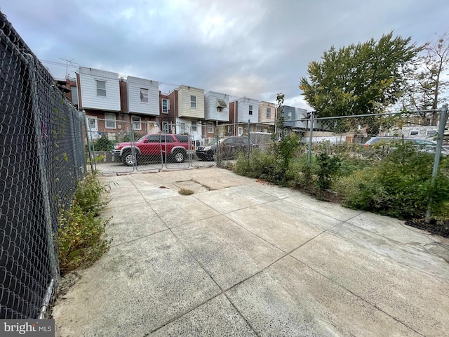 view of parking with fence, a residential view, and driveway