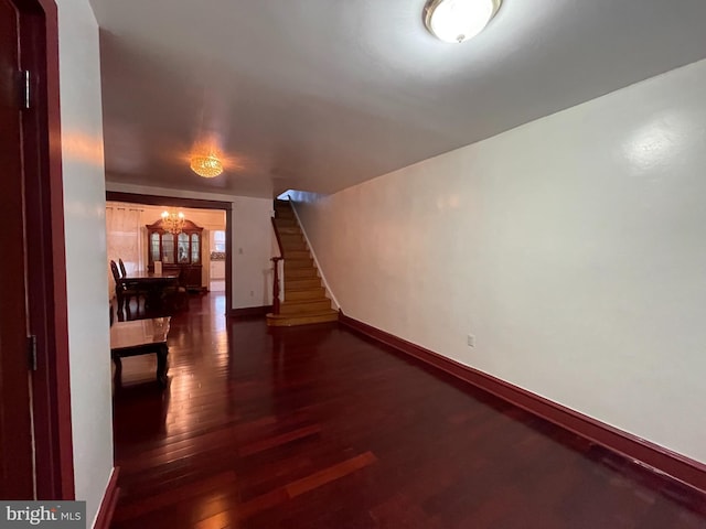 unfurnished living room with wood finished floors, baseboards, and stairway