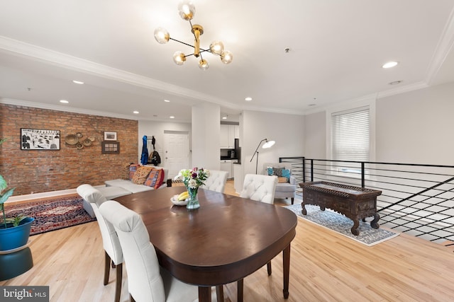 dining room with brick wall, light wood-style floors, a chandelier, recessed lighting, and crown molding