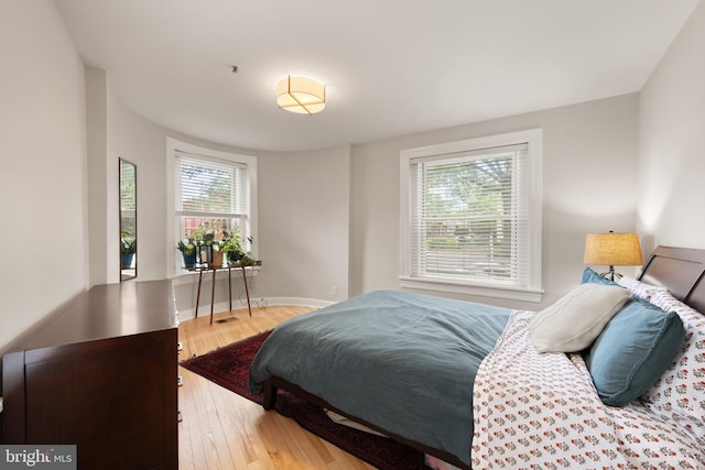 bedroom with multiple windows, wood finished floors, and baseboards