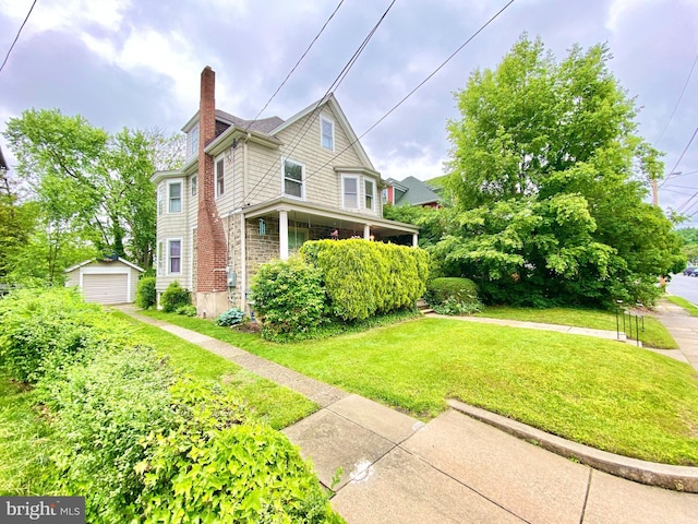view of home's exterior with a chimney, a lawn, an outdoor structure, and a detached garage