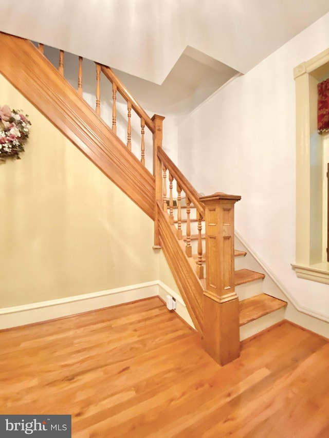 stairway with wood finished floors and baseboards