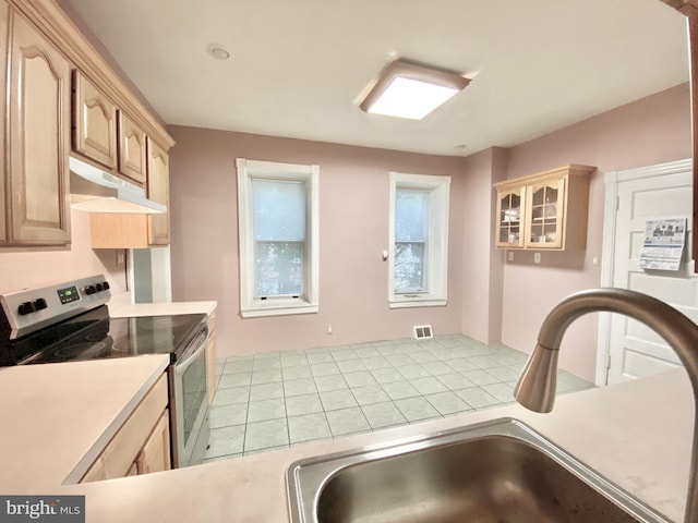 kitchen featuring under cabinet range hood, stainless steel range with electric stovetop, a sink, light countertops, and light brown cabinets