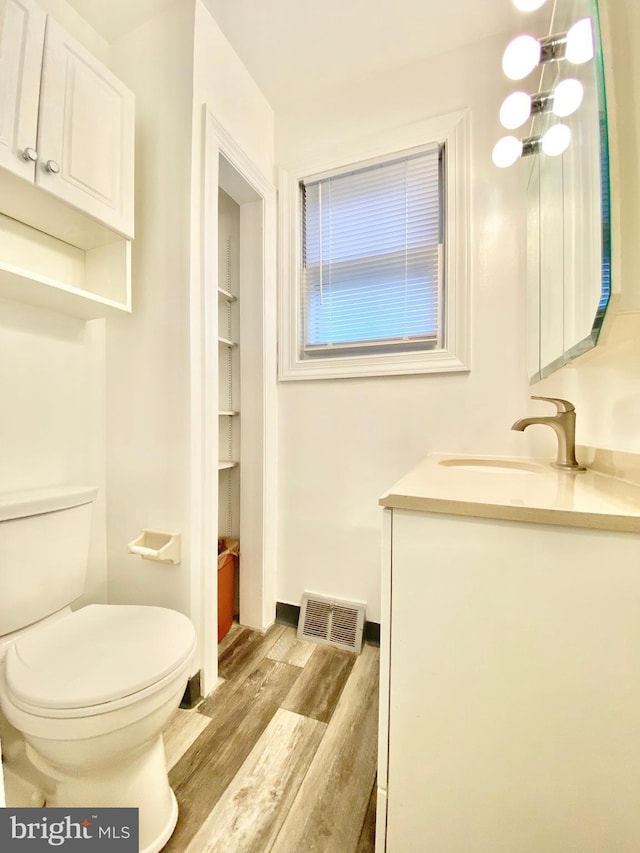 bathroom with wood finished floors, vanity, and toilet