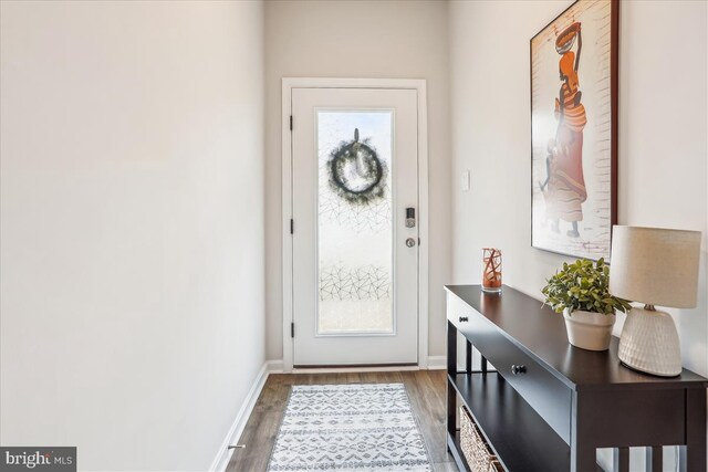 doorway with wood finished floors and baseboards