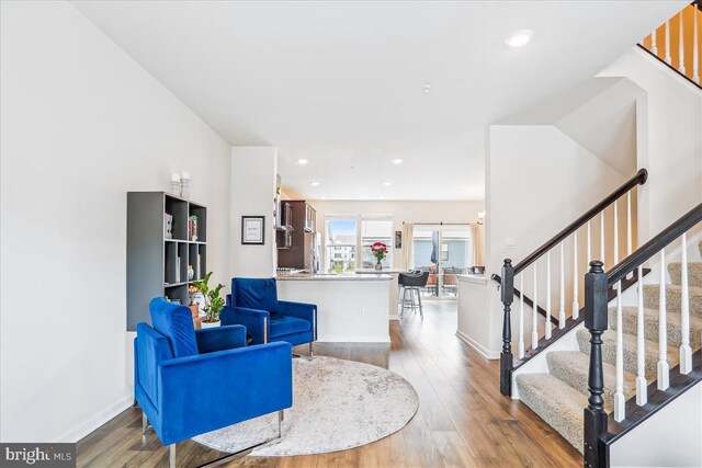 living area featuring wood finished floors, stairs, baseboards, and recessed lighting