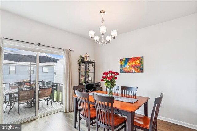 dining area featuring a chandelier, wood finished floors, and baseboards