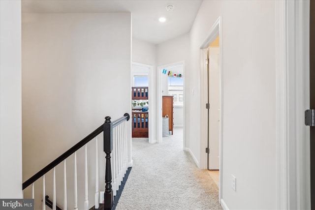 hall with an upstairs landing and carpet flooring