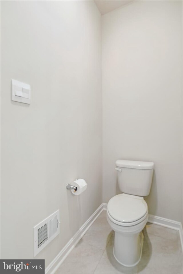 bathroom featuring baseboards, tile patterned flooring, and toilet