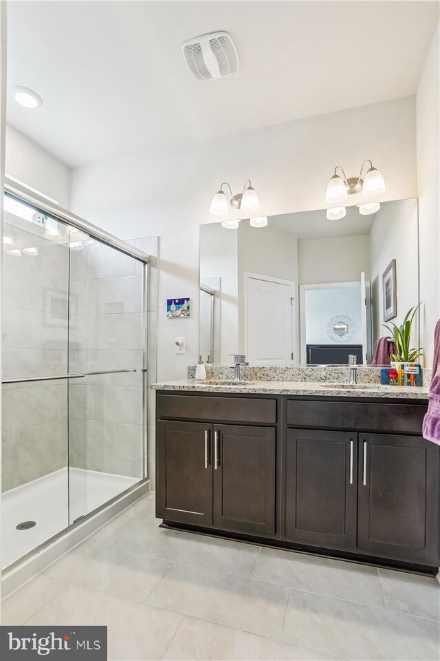 bathroom with a stall shower, tile patterned floors, and double vanity