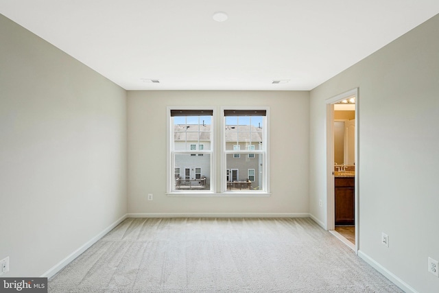 unfurnished room featuring baseboards and light carpet