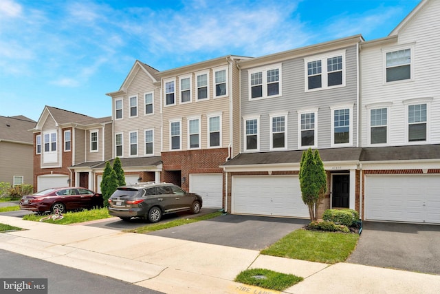 multi unit property with brick siding, a residential view, driveway, and an attached garage