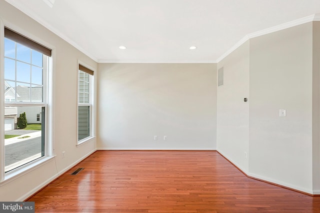 empty room with ornamental molding, wood finished floors, baseboards, and recessed lighting
