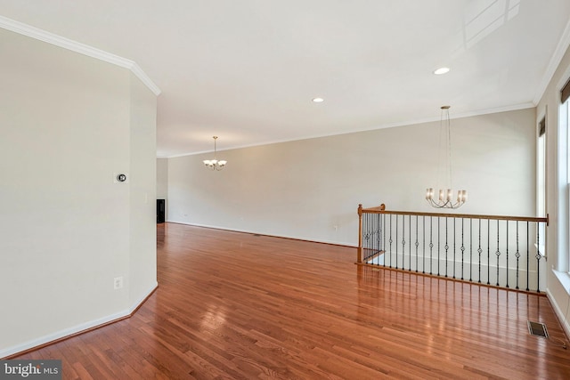 unfurnished room featuring a chandelier, wood finished floors, ornamental molding, baseboards, and recessed lighting